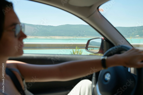 Wallpaper Mural A woman is driving a car with a scenic landscape visible through the windows, focusing on the road ahead. Torontodigital.ca