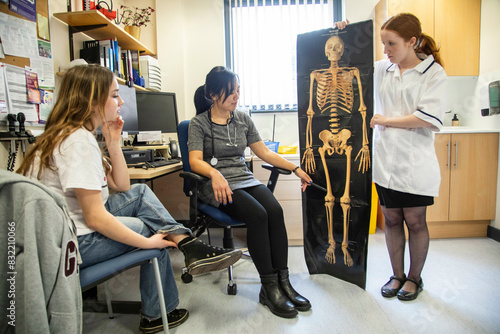 Doctor and assistant show skeleton picture to patient in a medical practice