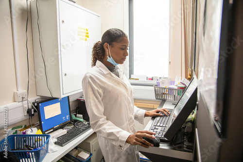 Female technician operating advanced machinery in a medical practice, UK photo