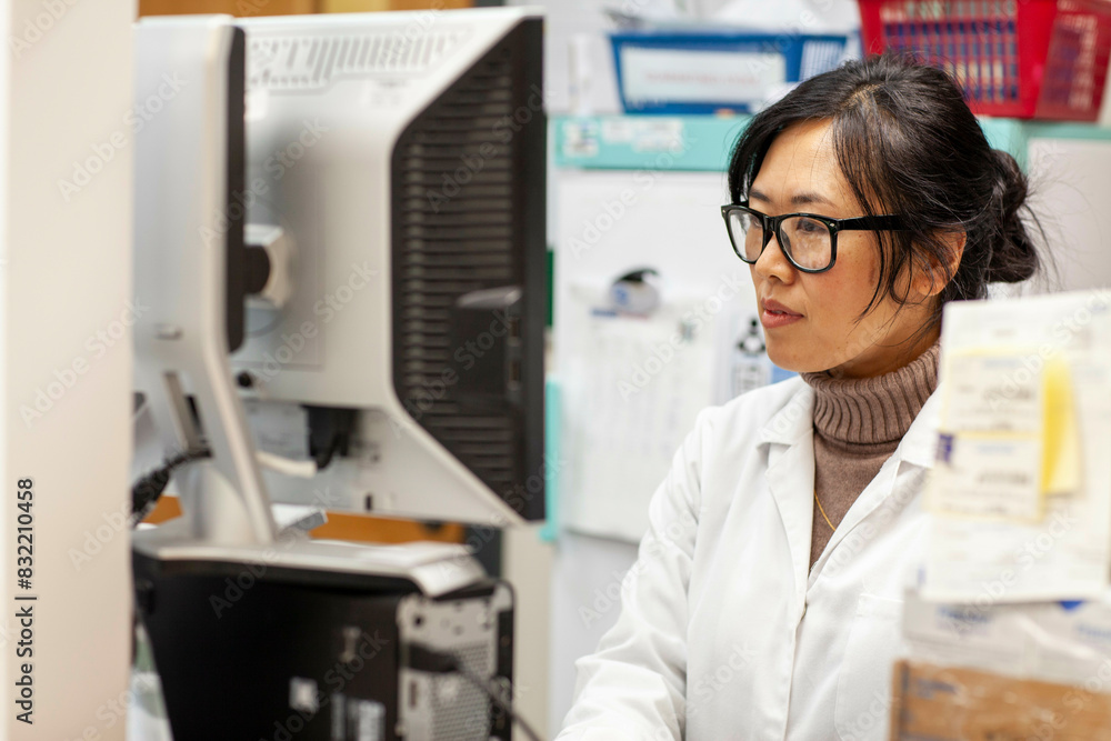 Scientist working at a computer in a lab, medical practice UK Scientist working at a computer in a lab, medical practice UK