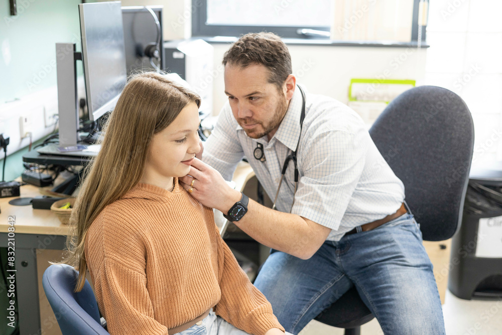 Doctor examining young patient's ear in clinic Doctor examining young patient's ear in clinic