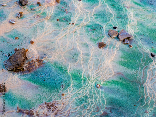 Textured hot spring with vibrant colors and stones photo