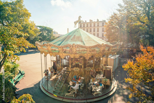 Sunlit vintage carousel in a tranquil park setting. photo
