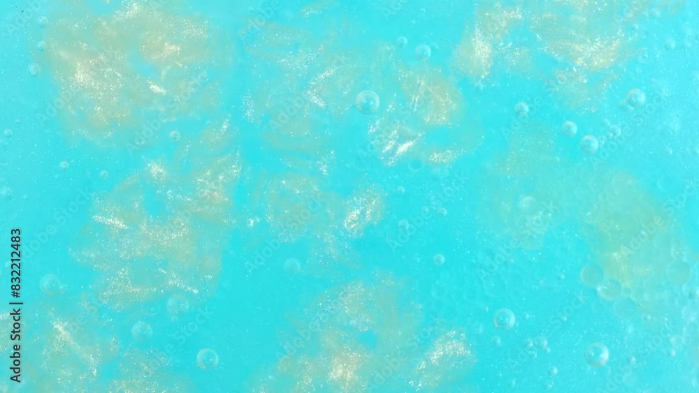 Shiny blue and golden gel fluid with bubbles, rotating. Macro texture of cosmetics product Shiny blue and golden gel fluid with bubbles, rotating. Macro texture of cosmetics product