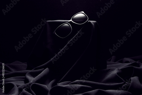 Black sun-protective glasses hanging on black cloth. photo