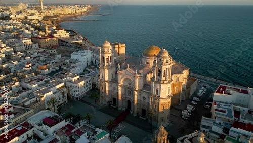 Drone rotating around the Cathedral of Cadiz at sunset. Beautiful warm colours reflecting on facade of the cathedral. Old and historic city situated in Andalucia Province, famous travel destination.  photo