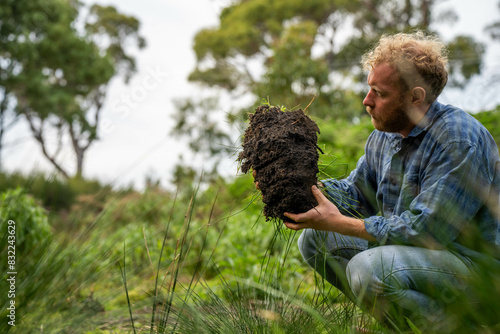 university student conducting research on forest health. farmer collecting soil samples in a test tube in a field. Agronomist checking soil carbon and plant health on a farm in australia photo