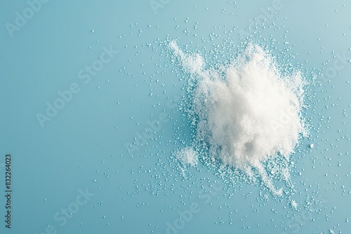 Sugar substitute granules exploding mid-air on blue background.