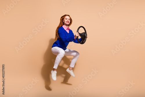 Full size photo of nice young woman jump hold wheel empty space wear pullover isolated on beige color background © deagreez