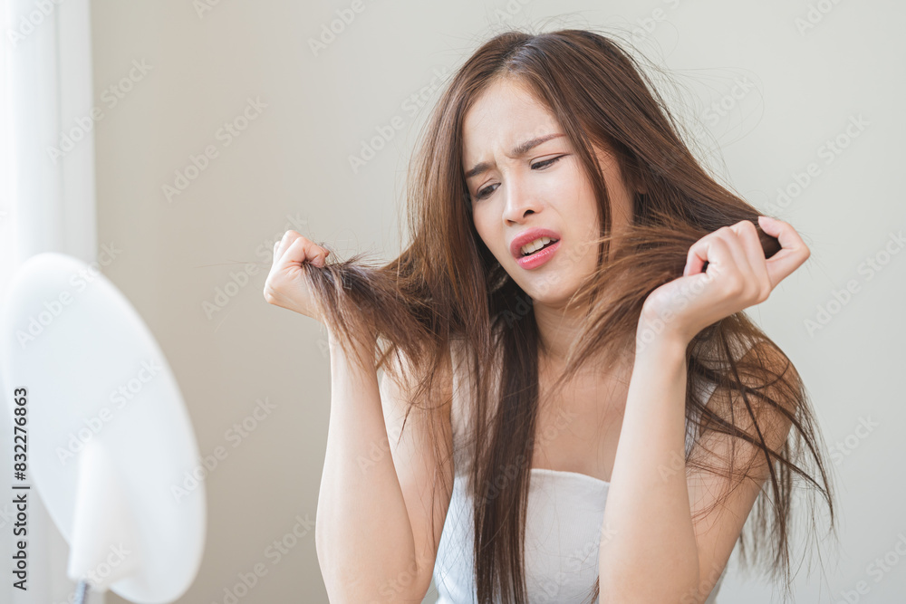 Damaged Hair, frustrated asian young woman, girl hand in holding splitting ends, messy unbrushed dry hair with face shock, long disheveled hair, health care of beauty. Portrait isolated on background. Damaged Hair, frustrated asian young woman, girl hand in holding splitting ends, messy unbrushed dry hair with face shock, long disheveled hair, health care of beauty. Portrait isolated on background.