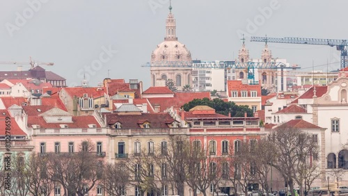 Aerial view over the center of Lisbon to the viewpoint called Miradouro de Sao Pedro de Alcantara timelapse. Colorful houses on a hill. Dome of Estrela basilica church. People in the park. Portugal photo