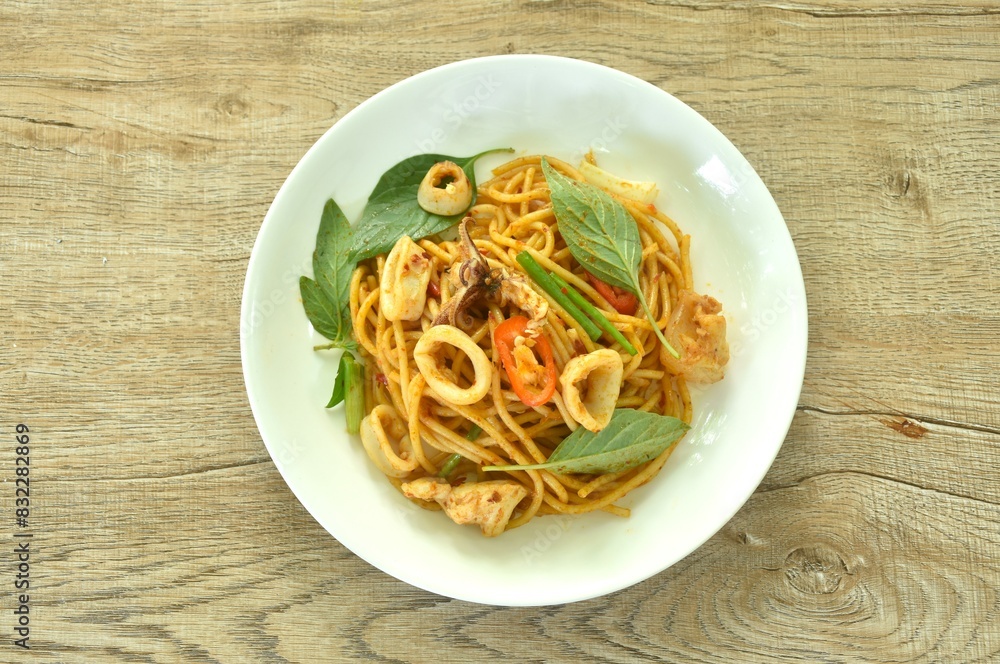 spicy stir fried spaghetti slice squid with chili and basil leaf in sauce on plate spicy stir fried spaghetti slice squid with chili and basil leaf in sauce on plate