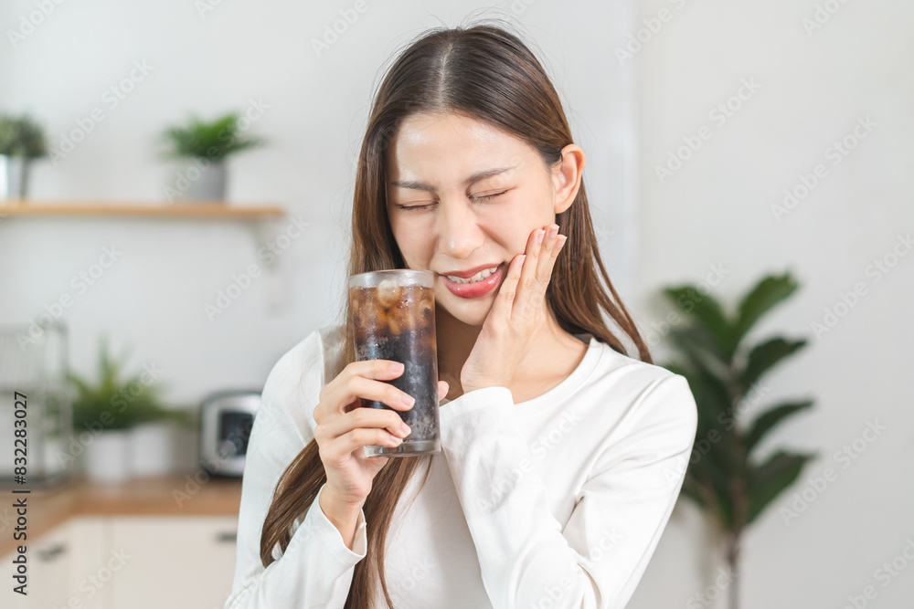 Health asian young woman touching her mouth, expression, suffering from toothache, decay or sensitivity cavity molar tooth or inflammation drink cold, sparkling water at home.Sensitive teeth people. Health asian young woman touching her mouth, expression, suffering from toothache, decay or sensitivity cavity molar tooth or inflammation drink cold, sparkling water at home.Sensitive teeth people.