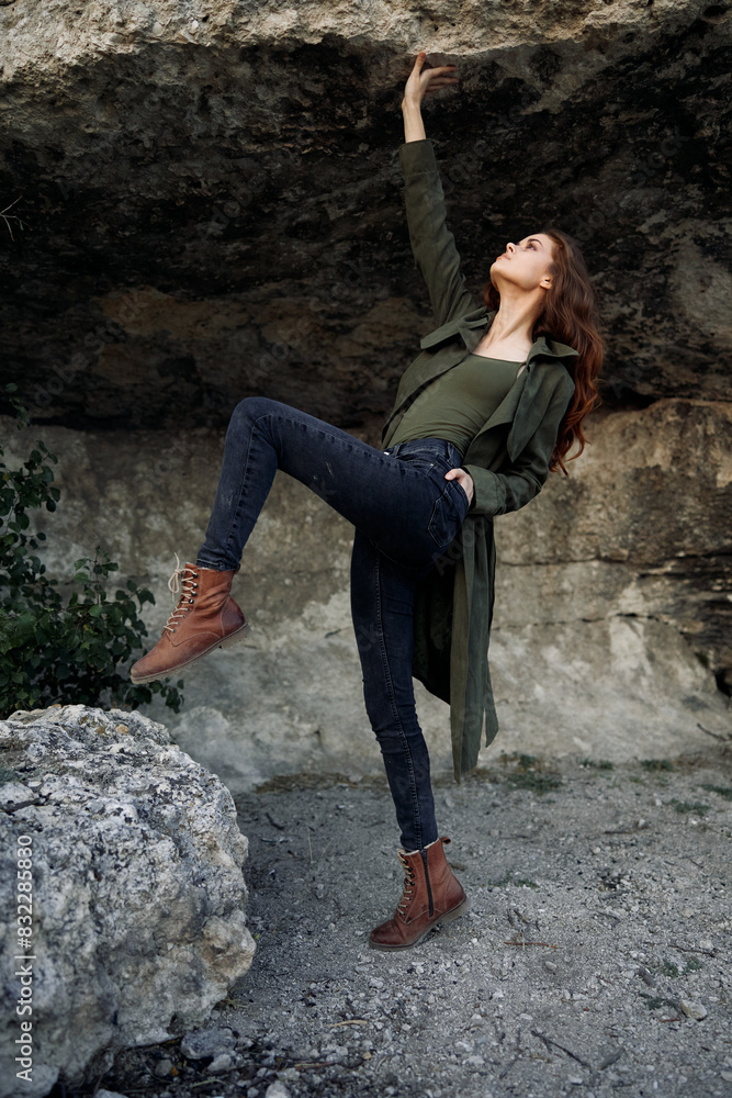 Woman standing on rock in forest wearing green coat and jeans Woman standing on rock in forest wearing green coat and jeans