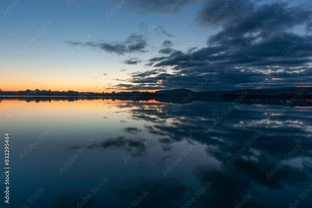 Silhouette with cloud reflections on calm bay Silhouette with cloud reflections on calm bay