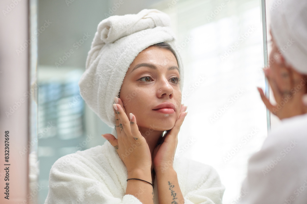 Young woman applying face cream after morning shower Young woman applying face cream after morning shower