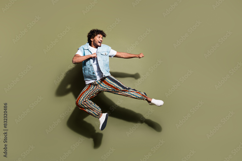 Full body photo of attractive young man jump kick karate dressed stylish denim clothes isolated on khaki color background Full body photo of attractive young man jump kick karate dressed stylish denim clothes isolated on khaki color background