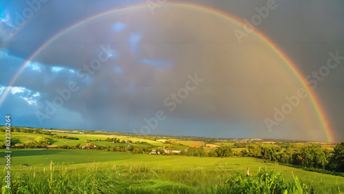 Glorious rainbow arching over the countryside after a passing rainstorm, with vibrant bands of color against a blue sky