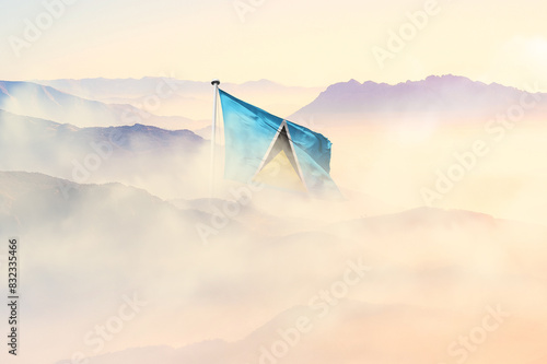 Saint Lucia flag disappears in beautiful clouds with fog. photo