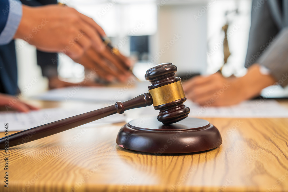 A team meeting of business people and a lawyer in formal suits is taking place at a desk, discussing a contract and various aspects of the law and litigation. A team meeting of business people and a lawyer in formal suits is taking place at a desk, discussing a contract and various aspects of the law and litigation.