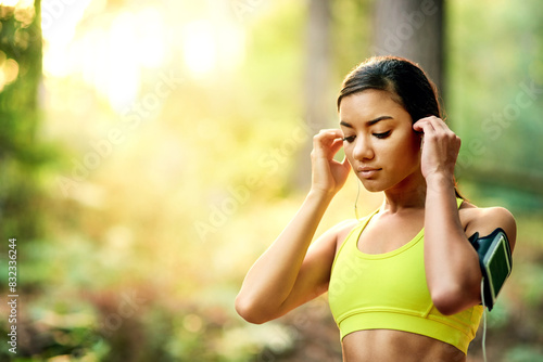 Nature, woman and smartphone for music before fitness, running and exercise for wellness with goals. Outdoor, female runner and headset for listening to podcast, radio and change playlist on mobile © peopleimages.com