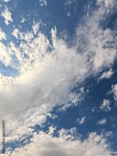 Stunning blue sky with fluffy white clouds, ideal for projects seeking tranquility and natural beauty. The camera rotates counterclockwise, revealing this serene and captivating scenery.