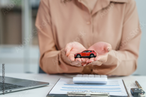 Asian businesswoman negotiates the sale of a car, discussing insurance and financing options, used car loans, premiums, deductibles, and various coverage types to ensure comprehensive protection. photo