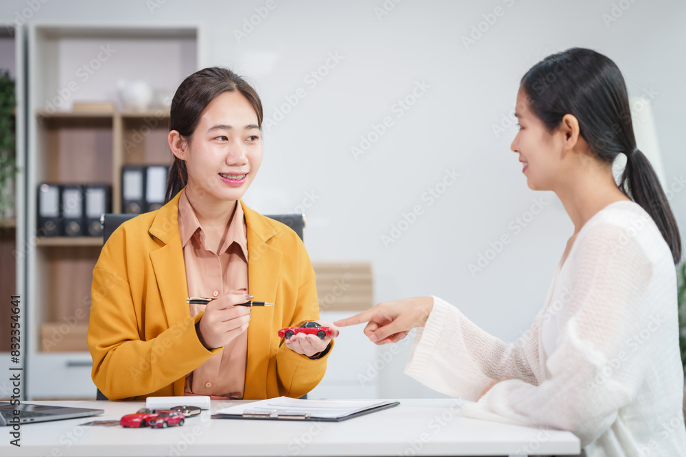 Asian businesswoman and a salesman discuss car sales, insurance, and financing with a customer at a desk, covering used car loans, premiums, deductibles, and various insurance coverage options. Asian businesswoman and a salesman discuss car sales, insurance, and financing with a customer at a desk, covering used car loans, premiums, deductibles, and various insurance coverage options.