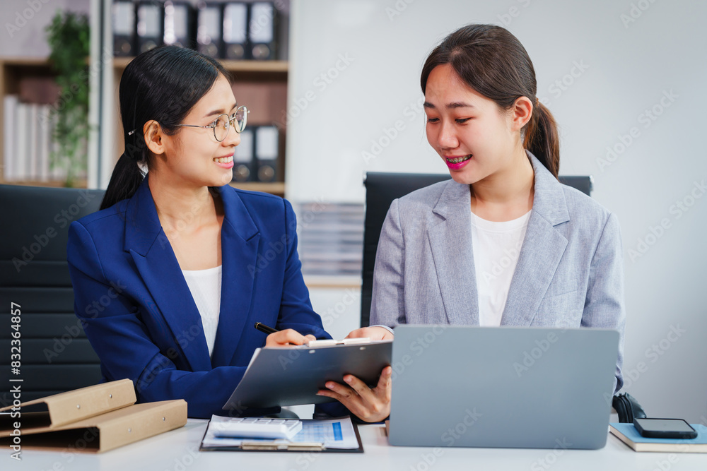Two Asian businesswomen collaborate on stock market strategies and financial services, exchanging comments and suggestions on loan applications and investment opportunities. Two Asian businesswomen collaborate on stock market strategies and financial services, exchanging comments and suggestions on loan applications and investment opportunities.