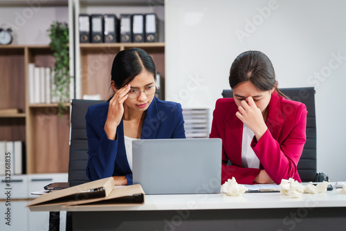 Two Asian businesswomen under stress and pressure discuss financial matters, experiencing anxiety and worry while navigating the complexities of the stock market and loan applications. photo