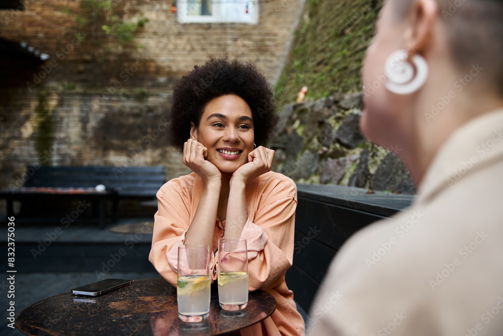 A woman sits at a table, calmly looking lovingly and cheerfully at her female partner. A woman sits at a table, calmly looking lovingly and cheerfully at her female partner.