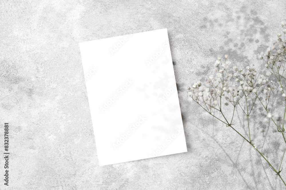 Fototapeta premium Blank wedding invitation card mockup with dry gypsophila flowers decor, copy space, top view