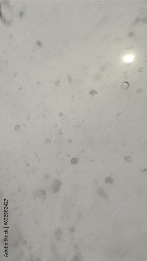 Vertical video, Bottom view of rain drops falling from a gray sky on the camera, slow motion, natural background Vertical video, Bottom view of rain drops falling from a gray sky on the camera, slow motion, natural background