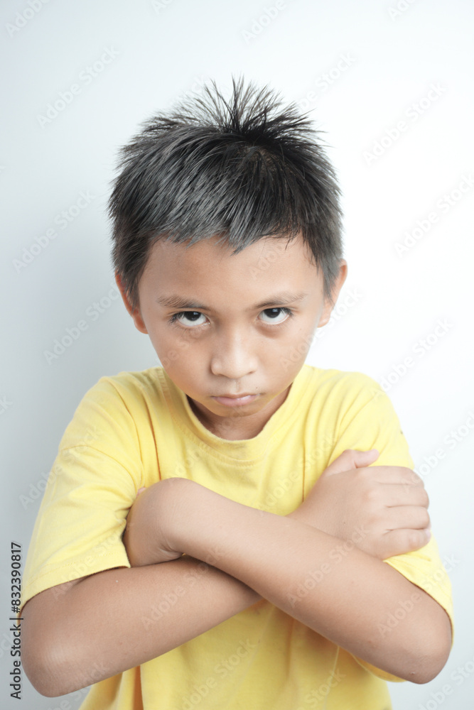 Angry little boy, yellow T-shirt over white background, sign and gesture concept Angry little boy, yellow T-shirt over white background, sign and gesture concept