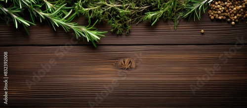 Sprigs of fresh fragrant rosemary in a bunch and other spices on a brown wooden background Copy space Flat layout View from above