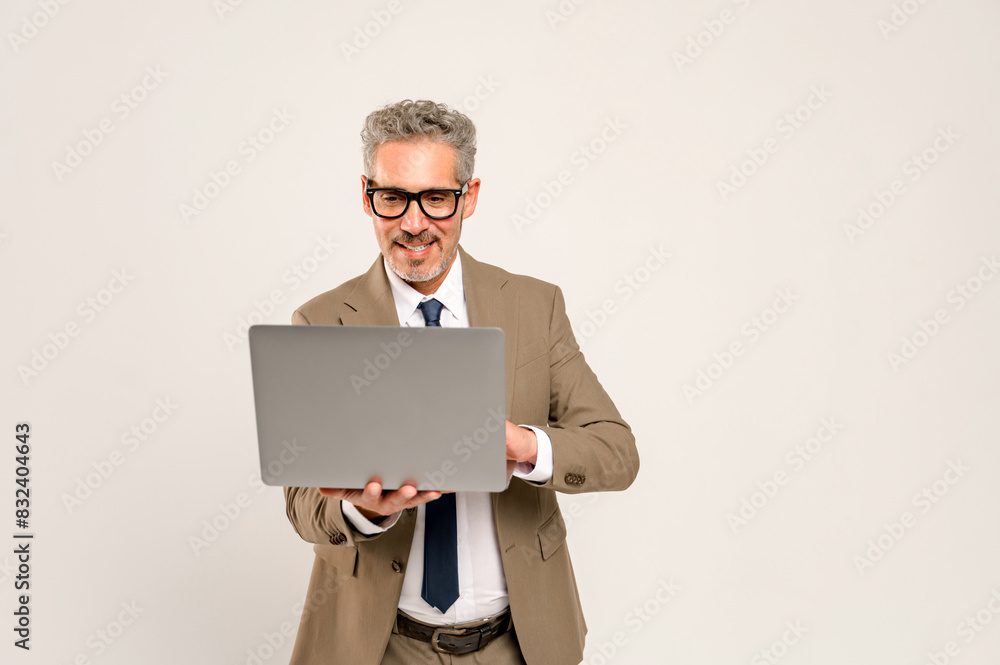 A charismatic grey-haired businessman looking at a laptop screen. This image captures the essence of modern business presentations or online communication, perfect for concepts related to technology A charismatic grey-haired businessman looking at a laptop screen. This image captures the essence of modern business presentations or online communication, perfect for concepts related to technology