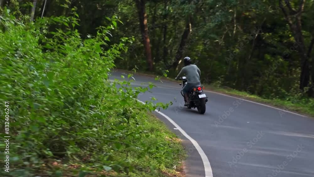 Young guy enjoying motorbike ride in the road passing by the forest, slow motion footage. Young guy enjoying motorbike ride in the road passing by the forest, slow motion footage.