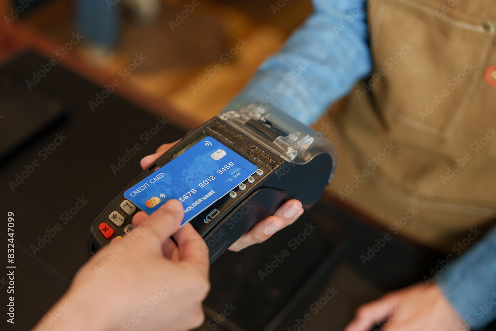 BaristaBusiness Girl Wearing dark blue shirt, wearing brown apron, held credit card machine. Let female customers use credit cards to pay for bakery coffee. cashless payment. small family business BaristaBusiness Girl Wearing dark blue shirt, wearing brown apron, held credit card machine. Let female customers use credit cards to pay for bakery coffee. cashless payment. small family business