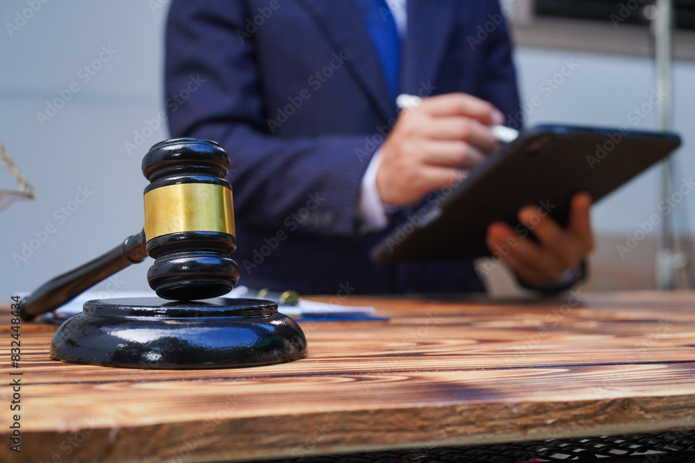 Hands of Asian and African male lawyers working with contract documents and wooden gavel on table in courtroom. Court judges and lawyers Hands of Asian and African male lawyers working with contract documents and wooden gavel on table in courtroom. Court judges and lawyers