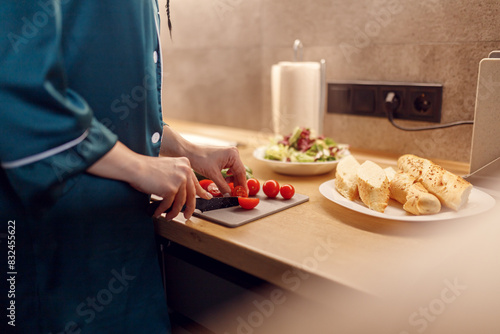 Young woman cooking vegetable summer salad in the home kitchen while chopping vegetables. Close up. Healthy food at home concept