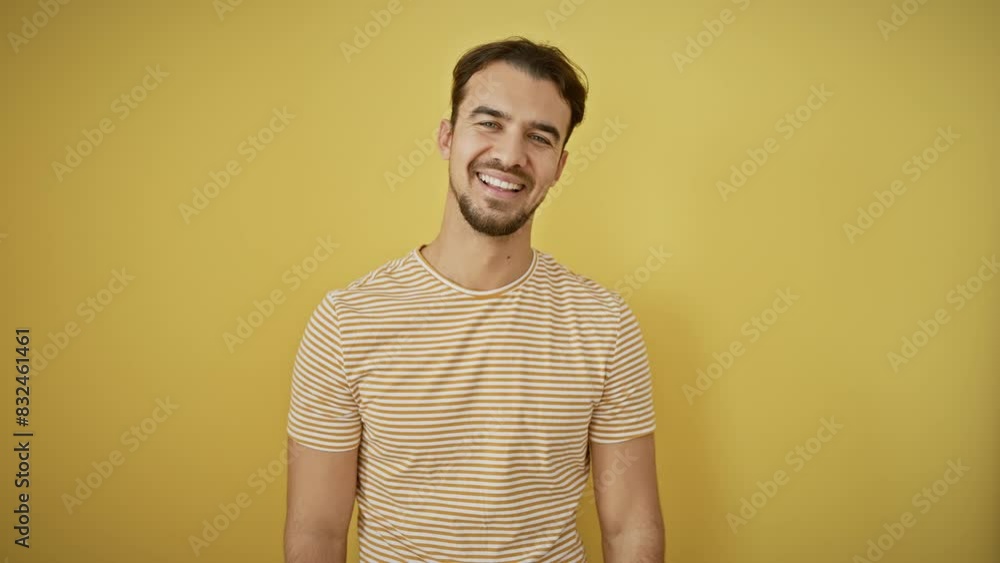Cheerful young hispanic guy, sporting a striped t-shirt, radiates positivity. he stands confident against a simple yellow backdrop, beaming a toothy, delighted smile. Cheerful young hispanic guy, sporting a striped t-shirt, radiates positivity. he stands confident against a simple yellow backdrop, beaming a toothy, delighted smile.