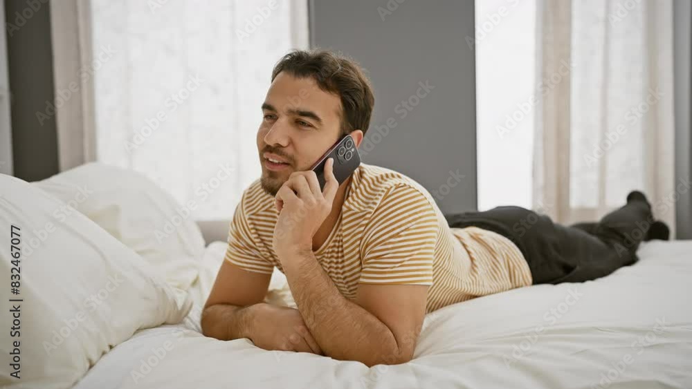 Handsome young man using smartphone while relaxing in bedroom, portraying a casual and comfortable lifestyle scene. Handsome young man using smartphone while relaxing in bedroom, portraying a casual and comfortable lifestyle scene.