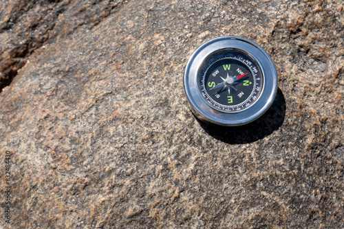 Brújula en primer plano sobre piedra arriba a la derecha en dia soleado