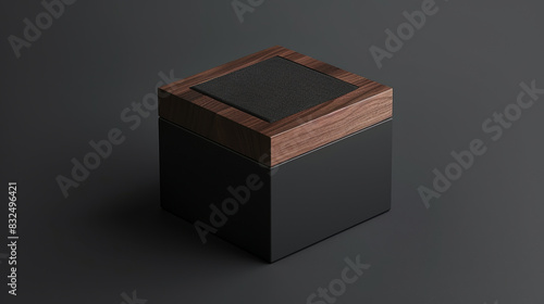 A modern, square packaging box with a black matte finish and a dark walnut wooden accent on the top, displayed in a trade show environment with sleek stands,