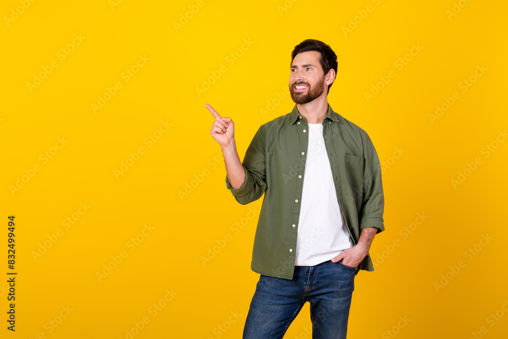 Photo of nice young man direct finger empty space wear khaki shirt isolated on yellow color background Photo of nice young man direct finger empty space wear khaki shirt isolated on yellow color background
