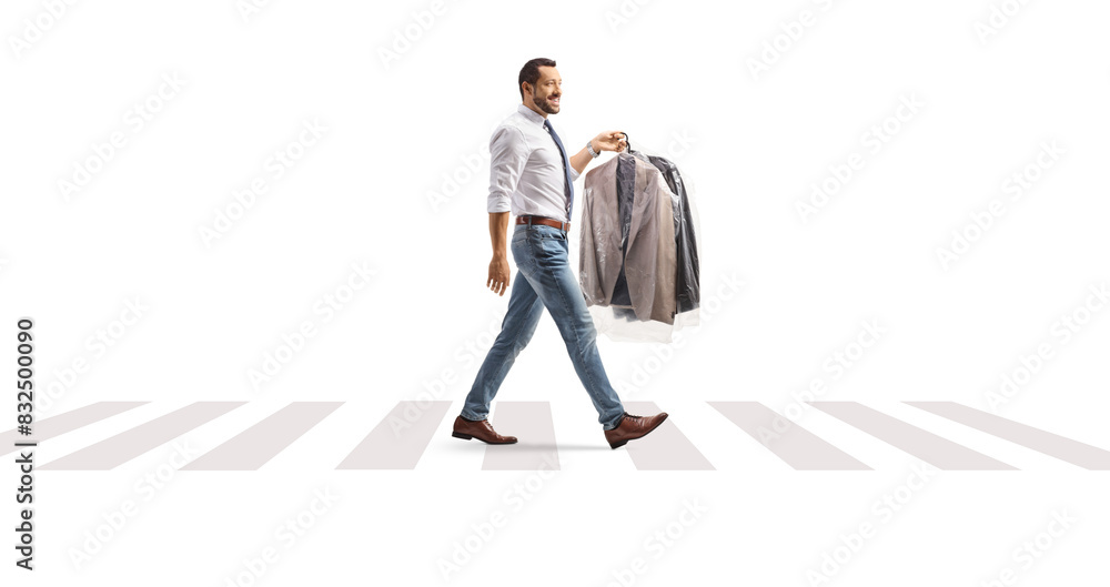 Full length profile shot of a man carrying suits on hangers and crossing a street Full length profile shot of a man carrying suits on hangers and crossing a street