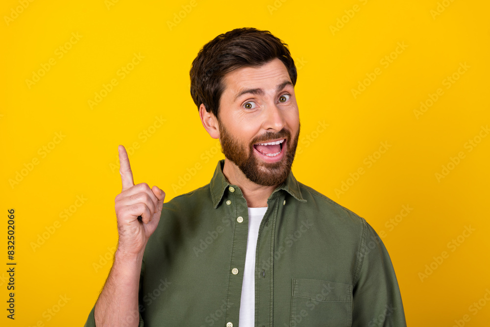 Photo of nice young man point finger wear khaki shirt isolated on yellow color background Photo of nice young man point finger wear khaki shirt isolated on yellow color background
