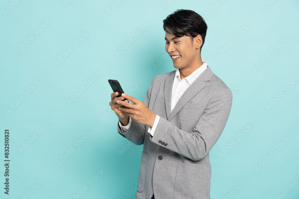 Happy Asian businessman typing or using mobile phone isolated on green background Happy Asian businessman typing or using mobile phone isolated on green background