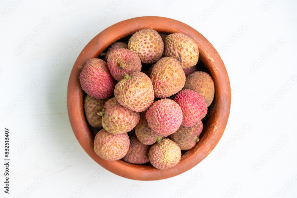 A clay pot filled with delicious ripe lychees. Top view. A clay pot filled with delicious ripe lychees. Top view.