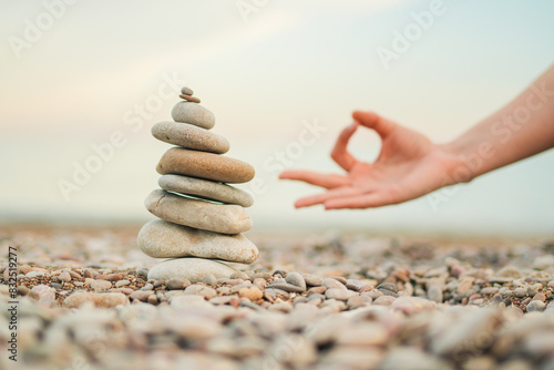 Bild auf Leinwand A hand is resting on a stack of rocks, with the hand's fingers touching the top of the stack